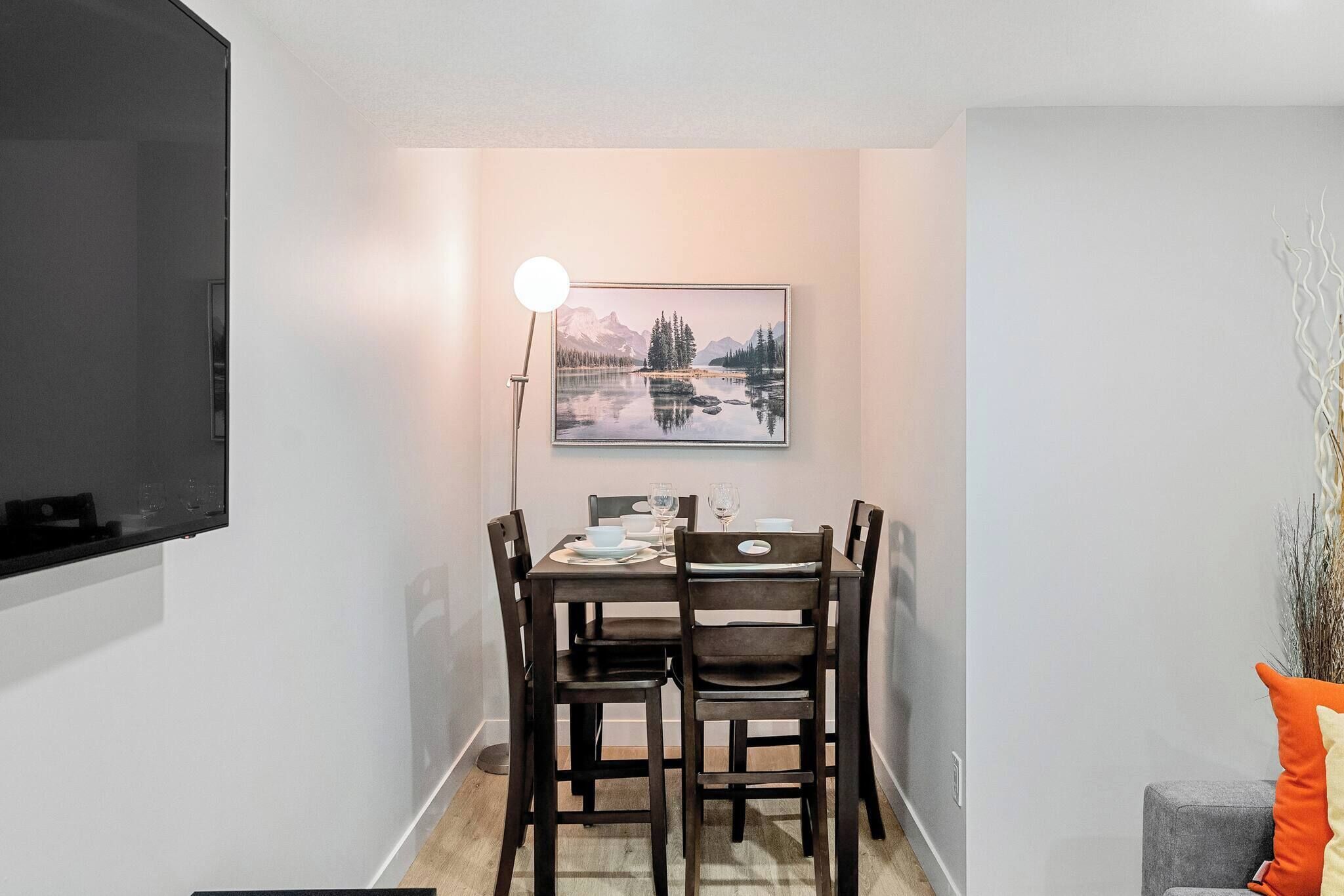 Ein Essbereich mit Tisch, Stühlen, einer Lampe und einem gerahmten Bild an der Wand.