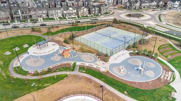 A residential area with a large sports court, playground, and a roundabout.