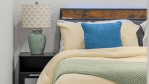 A bedroom with a bed, a nightstand, a lamp, and a window with blinds. - Latobir Modern,stylish 2BR Suite Private Entrance (Calgary)