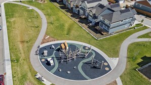 An aerial view of a residential area with a playground in the center, surrounded by houses and a curved road. - Latobir Modern,stylish 2BR Suite Private Entrance (Calgary)