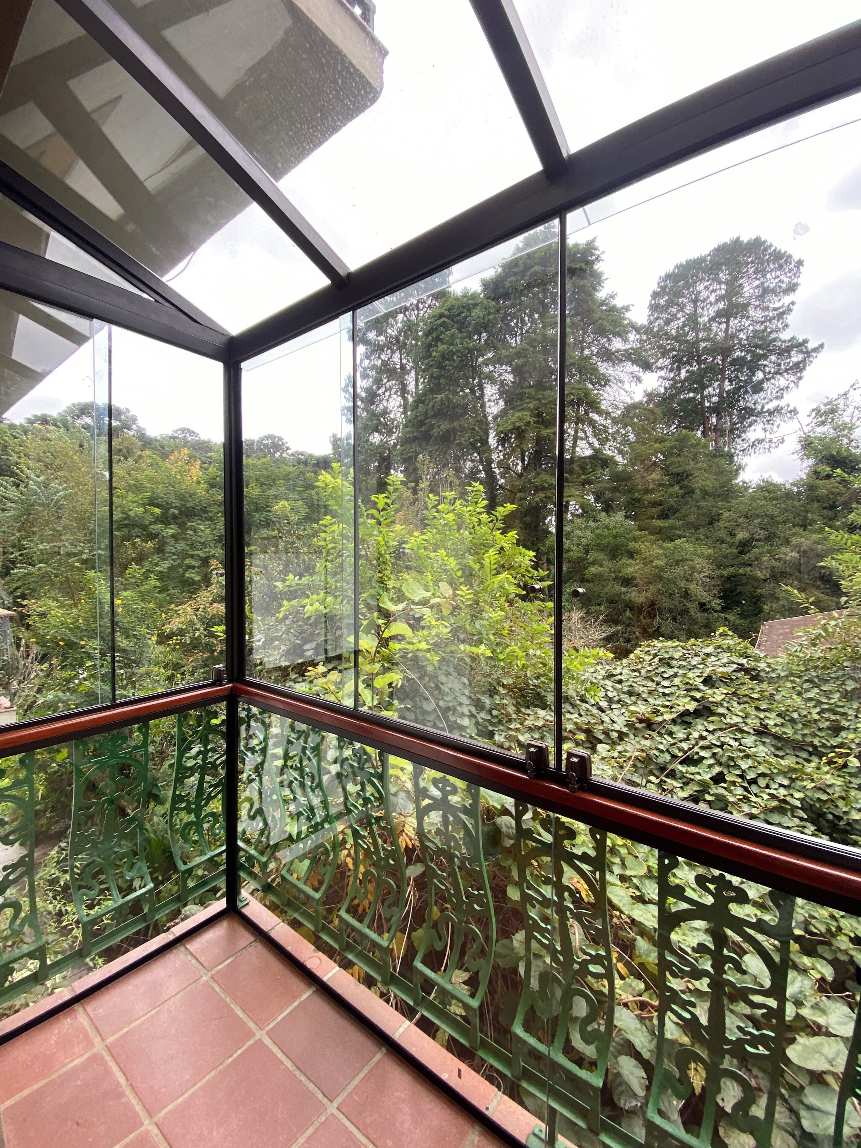 Une pièce dotée d’un mur en verre donnant sur un jardin luxuriant, où l’on peut admirer une variété de plantes et d’arbres.