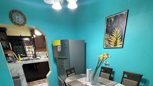 A dining area with a table, chairs, a fan, a clock, and a refrigerator. - Luxury house in soothing Spanish Town perfect for your getaway (Spanish Town)