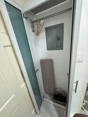 Ein schmaler, geschlossener Raum mit einer Tür, einem kleinen Fenster und einer Metallvorrichtung an der Wand.