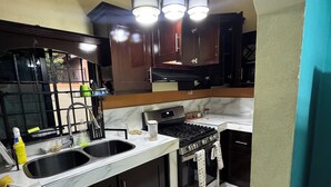 A kitchen with a double sink, stove, and dark wooden cabinets. - Luxury house in soothing Spanish Town perfect for your getaway (Spanish Town)