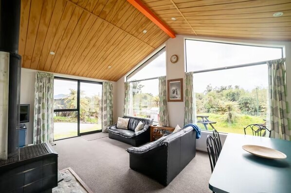 A spacious living area with a large window, a sofa, a table, and a fireplace.