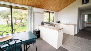 Eine moderne Küche mit Holzboden, großen Fenstern und einem Essbereich mit Tisch und Stühlen.