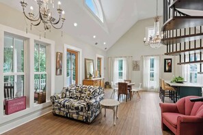 A spacious living room with a large sofa, a dining area, and a staircase.