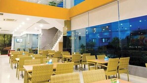 A modern indoor dining area with wicker furniture and glass walls. - Borneo Hotel (Pontianak)
