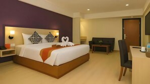 A hotel room with a large bed, a desk, a chair, and a sofa. - Borneo Hotel (Pontianak)