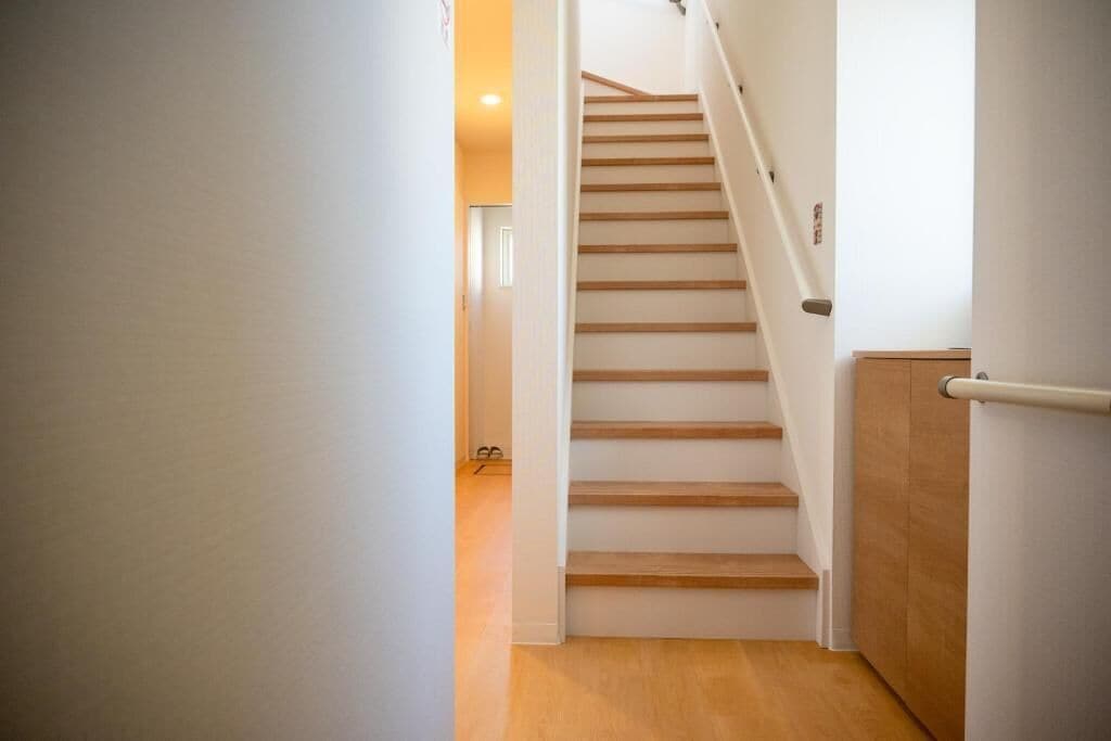 A staircase with wooden steps and a handrail, leading to a room with a door.