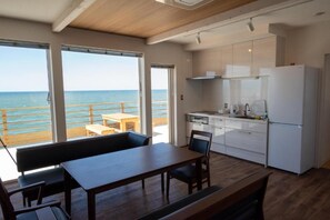 A modern kitchen with white cabinets and a view of the ocean through large windows.