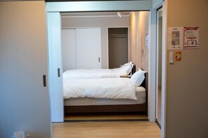 Habitació d'hotel amb un llit, un armari i una taula petita.