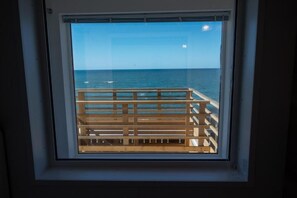 A window with a view of the ocean and a wooden deck.