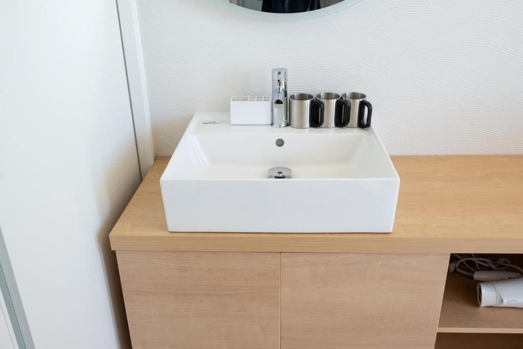 A bathroom with a white sink, a mirror, and a wooden countertop.