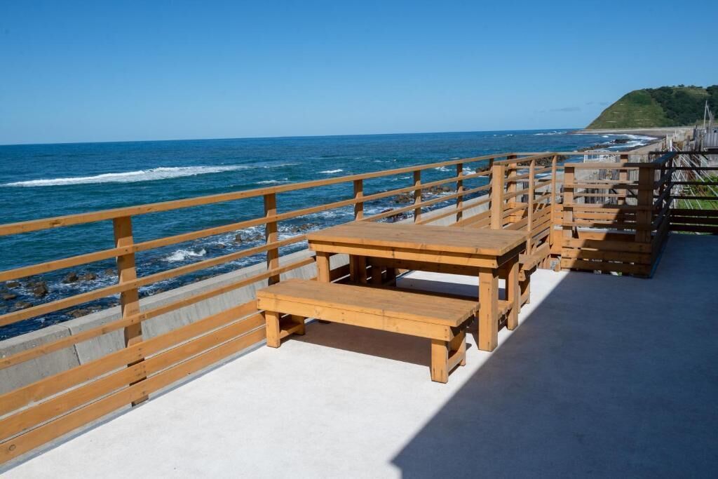 A wooden deck with benches overlooking a beach and ocean.