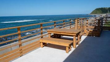 A wooden deck with benches overlooking a beach and ocean.