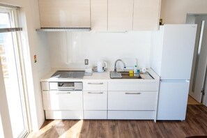 A compact kitchen with white cabinets, a built-in oven, a sink, and a refrigerator. - STAY in Obira (Obira)