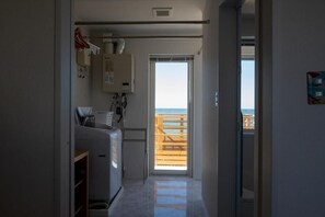 A narrow hallway leading to a balcony with a wooden railing, a small kitchenette with a refrigerator, and a door leading outside. - STAY in Obira (Obira)