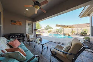 Eine Außenpatio mit Pool, Sitzbereich und Deckenventilator.