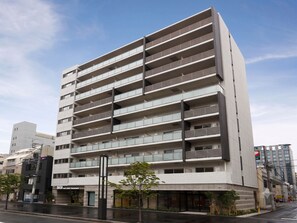 A multi-story building with a modern architectural design, featuring a series of balconies and a ground-level entrance. - Dash Living Toranomon (Minato-ku)