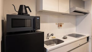Ett modernt kök med en svart mikrovågsugn, en kaffebryggare, en diskho och en bänkskiva.