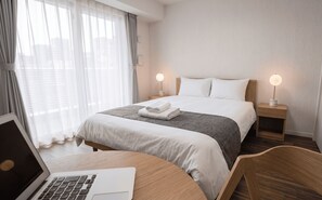 A hotel room with a bed, bedside lamps, a laptop on a desk, and a chair. - Dash Living Toranomon (Minato-ku)
