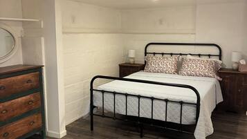 A bedroom with a bed, dresser, bedside tables, and a window.