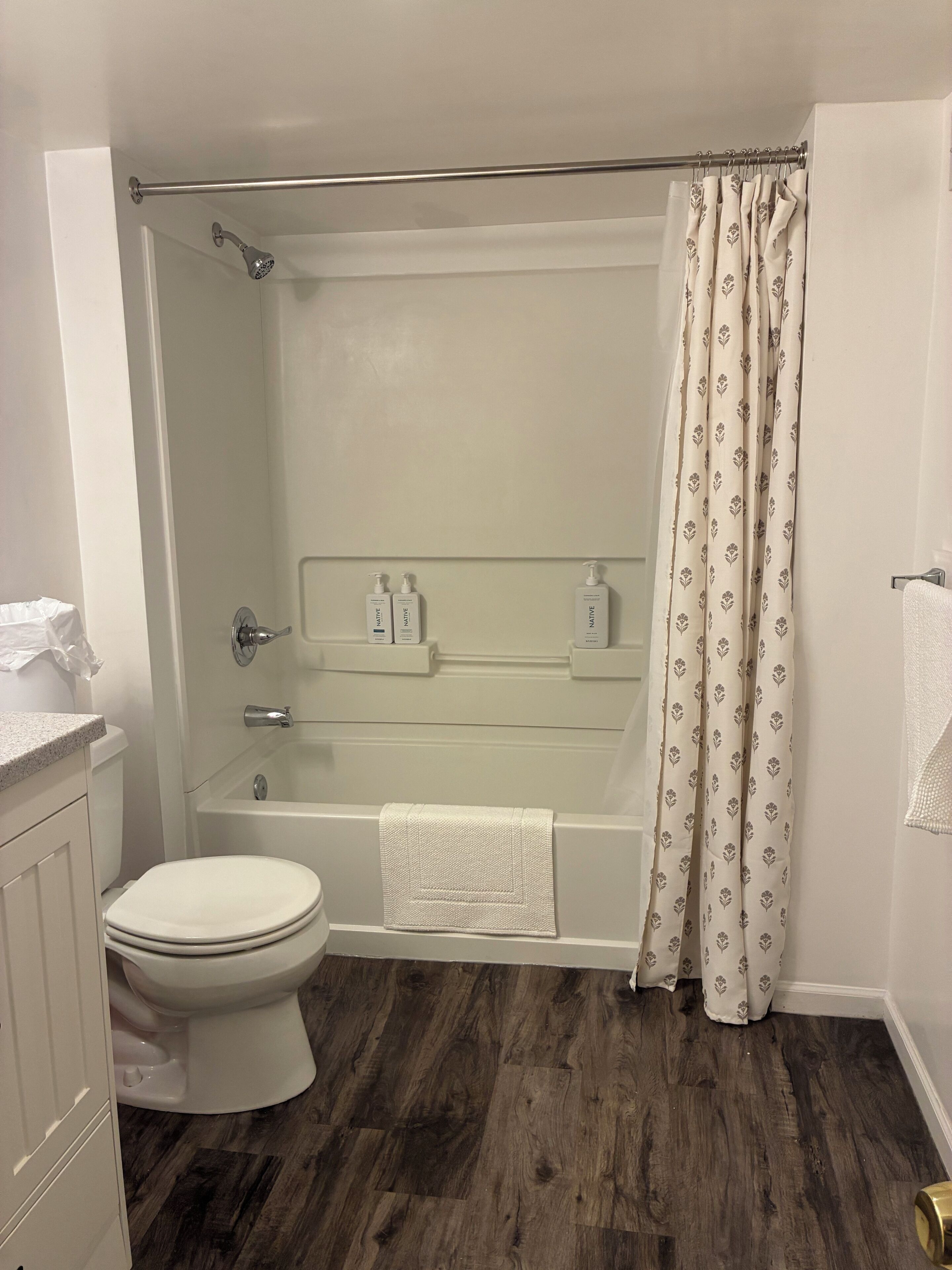 A bathroom with a toilet, a bathtub, a shower, and a toilet paper holder.
