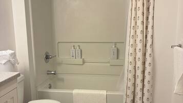 A bathroom with a toilet, a bathtub, a shower, and a toilet paper holder.