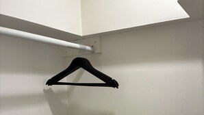 Un armario con pared blanca, piso de madera y rejilla blanca.