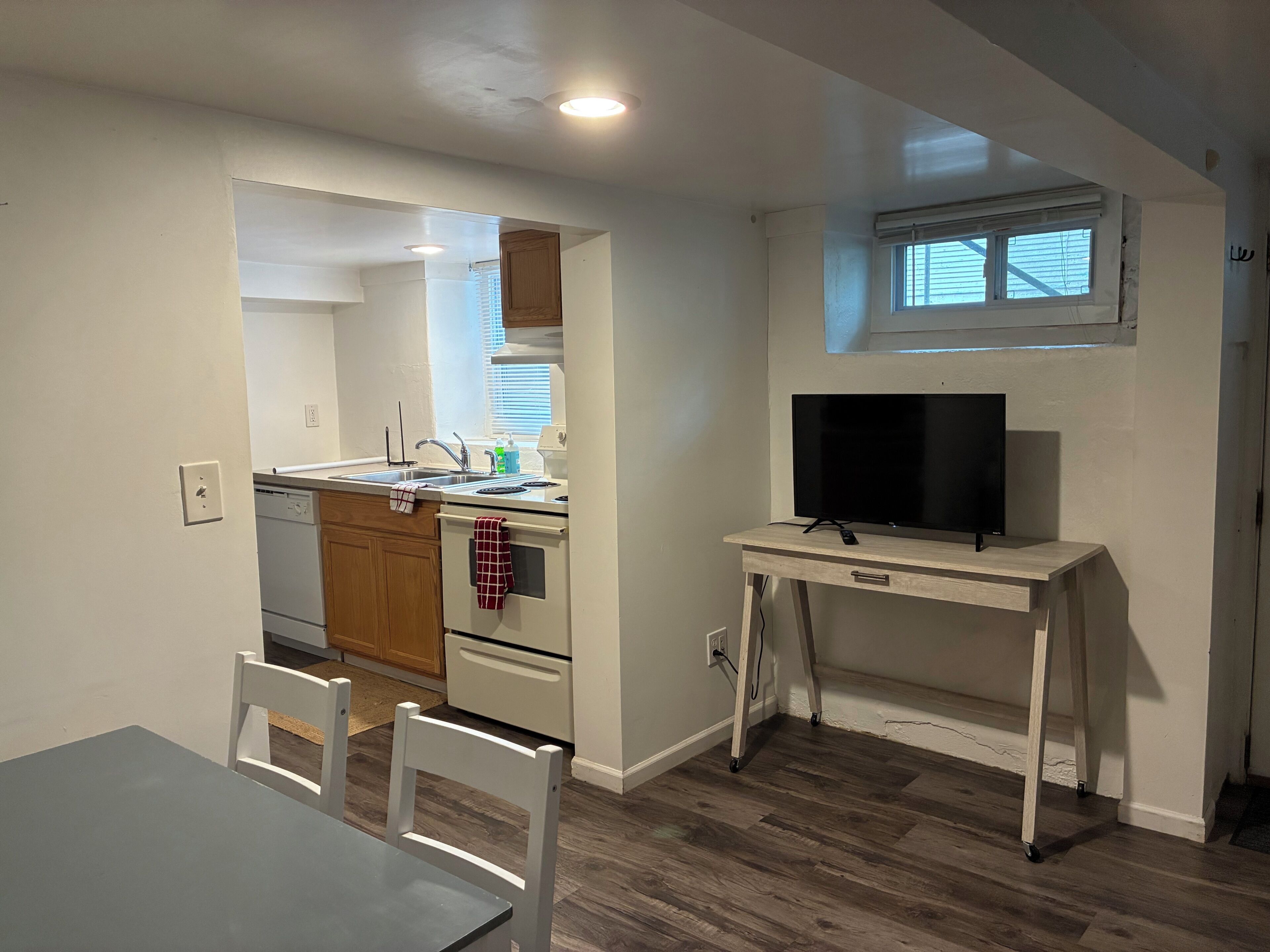 A compact kitchen with a sink, stove, and a TV on a small table.