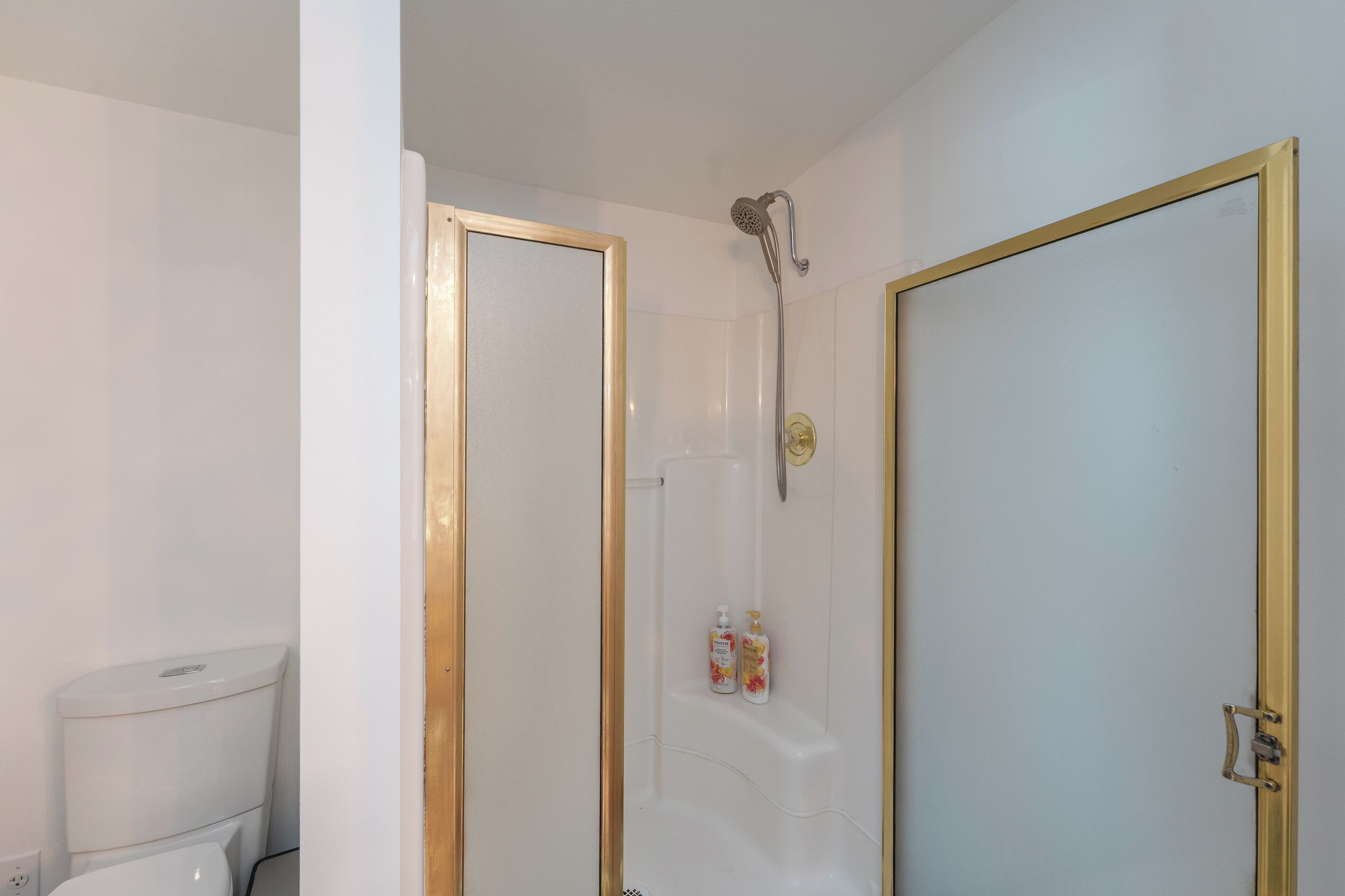 Un baño con ducha, inodoro y dos puertas.
