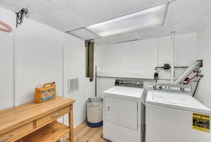 A laundry room with a washing machine, dryer, and a table with a detergent bottle. - Golden Splash, HotTub & Fire Pit, 15 Min2CVG (Florence)