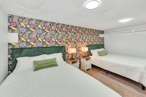 A room with two beds, a green headboard, a patterned wall, and a nightstand with a lamp. - Golden Splash, HotTub & Fire Pit, 15 Min2CVG (Florence)