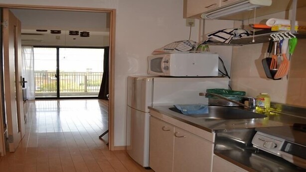Cocina equipada con microondas, estufa y lavamanos. Hay una puerta ventana que da a un espacio exterior.