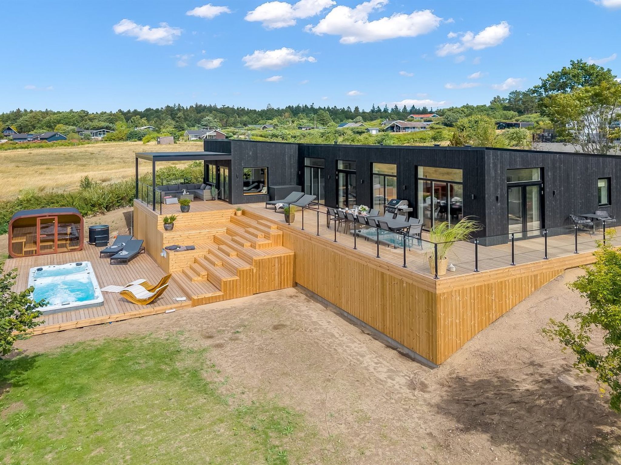 Een modern huis met een houten terras, zitplaatsen buiten en een jacuzzi.