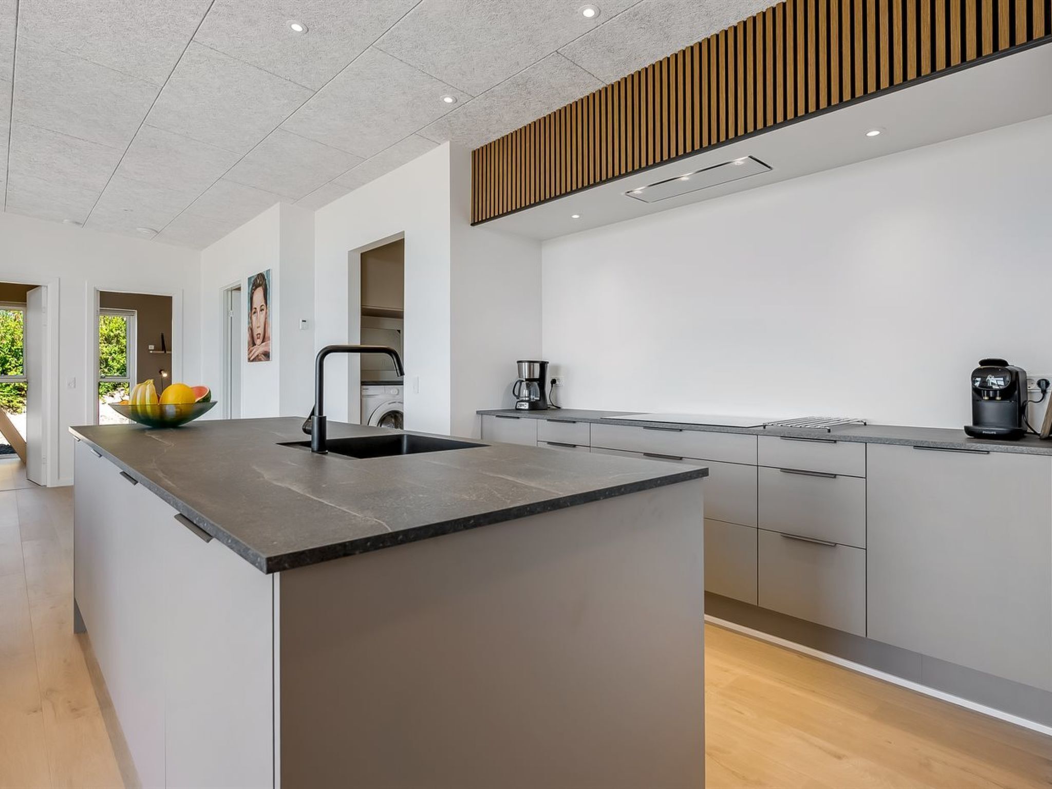A modern kitchen with a central island, a built-in oven, and a coffee maker.