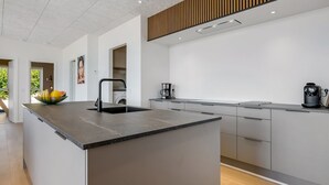 Een moderne keuken met een centraal kookeiland, een inbouwoven en een koffiezetapparaat.