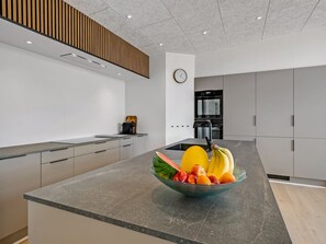 A modern kitchen with a central island, built-in appliances, and a clock on the wall. - "Hubertina" - 900m from the sea by Interhome (Ebeltoft)