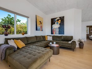 Una sala de estar moderna con un sofá modular, una mesa de centro y dos cuadros en la pared.