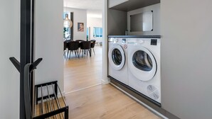 Een moderne wasserij met twee voorladers, een magnetron erboven en een eethoek op de achtergrond.