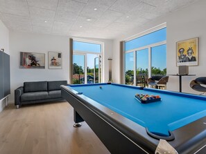 A modern indoor pool area with a pool table, a sofa, and large windows offering a view of the outdoors. - "Hubertina" - 900m from the sea by Interhome (Ebeltoft)