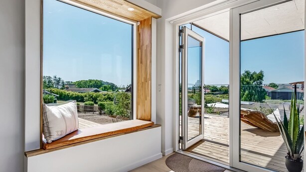 Een kamer met een groot raam, een schuifpui en uitzicht op een tuin.