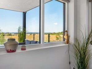 A room with a large window overlooking a field, a vase, and a small plant on the windowsill. - "Hubertina" - 900m from the sea by Interhome (Ebeltoft)