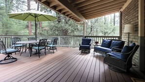 En overdækket terrasse med et bord, stole, en sofa og en parasol.