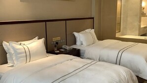 A hotel room with two beds, a nightstand, a telephone, and a mirror.