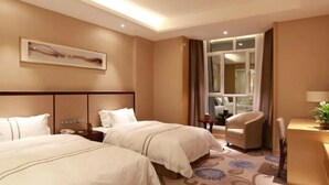 A hotel room with two beds, a desk, a chair, and a window with curtains.