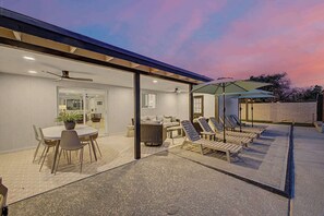 Eine Außenpatio mit Essbereich, Liegestühlen und Sonnenschirmen.