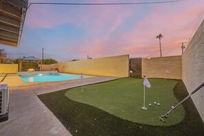 A backyard with a swimming pool, artificial turf, and a golf putting area. - NEW Ocotillo Luxe Retreat Scottsdale Old Town (Scottsdale)
