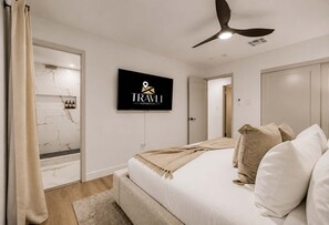 A modern hotel room with a bed, a television, a ceiling fan, and a bathroom with marble tiles. - NEW Ocotillo Luxe Retreat Scottsdale Old Town (Scottsdale)